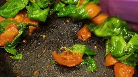 Making stewed tomatoes and spinach in a frying pan Stock Footage 341616654
