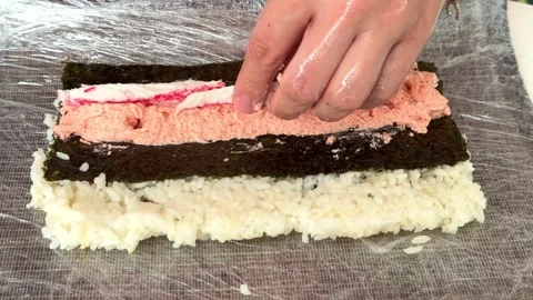 Making sushi rolls with layers of rice and fish in a kitchen at home 스톡 동영상 331901521