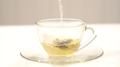 Making tea with tea bag in a cup glass pouring hot water Video stock 109560574