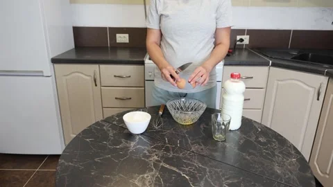 Making thin pancakes with milk. A pregnant woman makes pancakes in the kitchen a Stock Footage 317535308