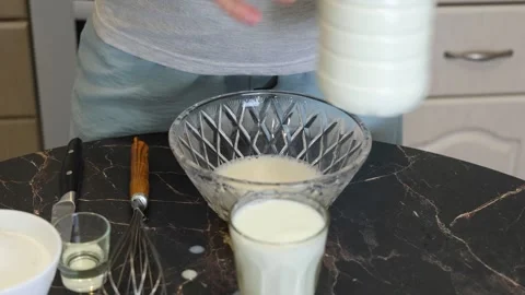 Making thin pancakes with milk. A pregnant woman makes pancakes in the kitchen a Stock Footage 317535501