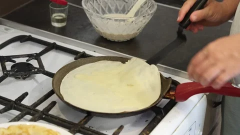 Making thin pancakes with milk. A pregnant woman makes pancakes in the kitchen a Stock Footage 317536116