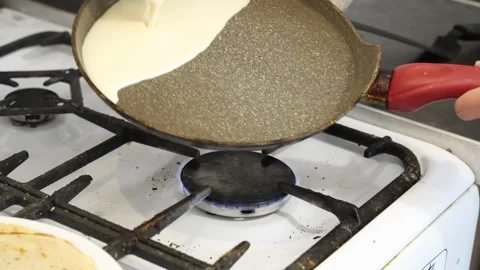 Making thin pancakes with milk. A pregnant woman makes pancakes in the kitchen a Stock Footage 317536251