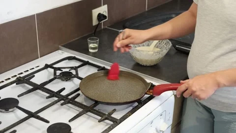 Making thin pancakes with milk. A pregnant woman makes pancakes in the kitchen a Stock Footage 317536279