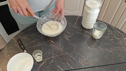 Making thin pancakes with milk. A pregnant woman makes pancakes in the kitchen a Stock Footage 317536844