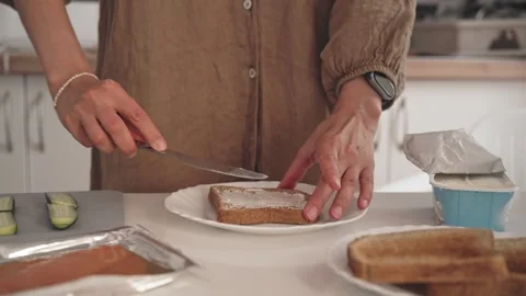 Making toast with jam in a kitchen, spreading on bread with a knife and preparin Видео 338166793