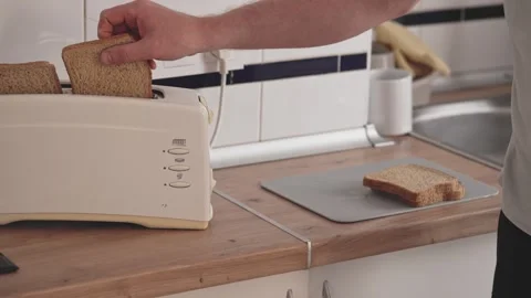 Making toast in a kitchen using a toaster with sliced bread at breakfast time Stock Footage 338166816