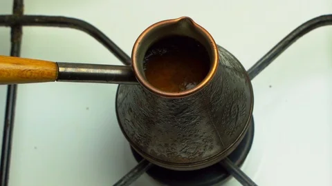 Making turkish coffee in copper cezve over gas stove. On the gas stove Turk with Stock Footage 119061372