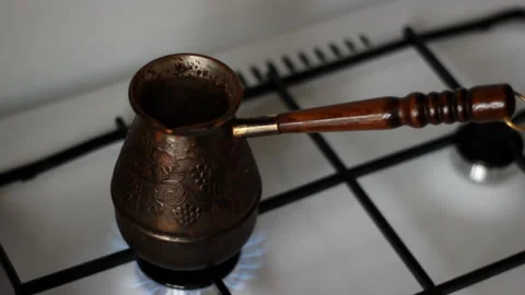 Making turkish coffee in copper cezve over gas stove. On the gas stove Turk with Stock Footage 123455822