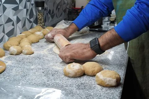 Making unleavened flatbread. A man's hands roll out the dough with a rolling pin Stock Photos