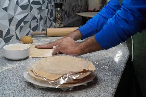 Making unleavened flatbreads. A man's brown hands touch a flatbread. Stock Photos