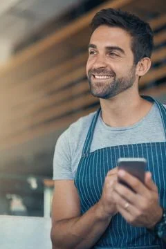 Making use of coffee shop management apps. Shot of a young man using a mobile Stock Photos