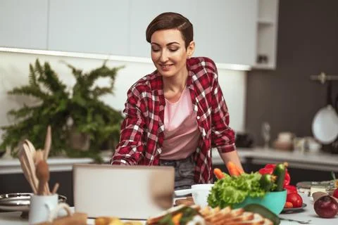 Making a video call using laptop computer housewife while cooking or baking Stock-Fotos