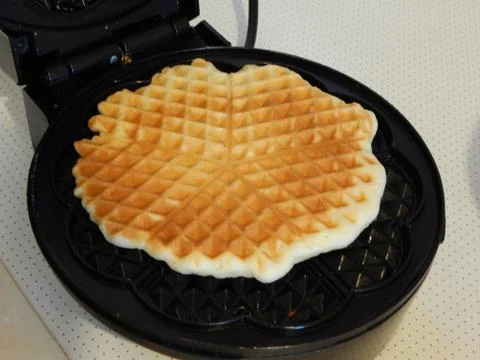 Making waffles on biscuit baking machine at home Stock Photos