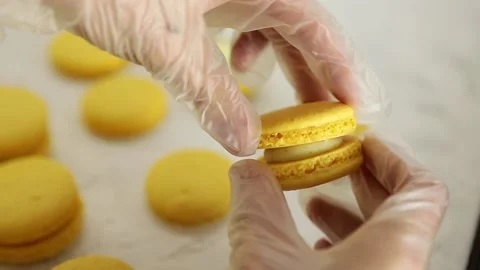 Making Yellow Macaroons. Close up shot of connecting two halves of macaroons Video stock 130983705