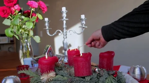 Mal hand is lighting red decorative christmas candles on a wooden table Stock Footage 74472016