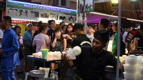 Malacca, Malaysia - May 5th, 2018 - Coconut seller throwing coconuts Stock Footage 115029454