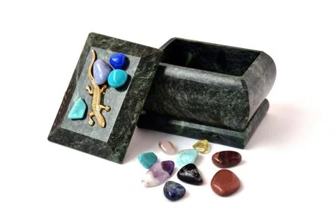 Malachite box and a scattering of multi-colored stones on a white background Stock Photos