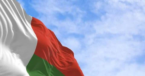Malagasy flag of Madagascar waving in wind on clear blue sky. 3D render イラスト素材