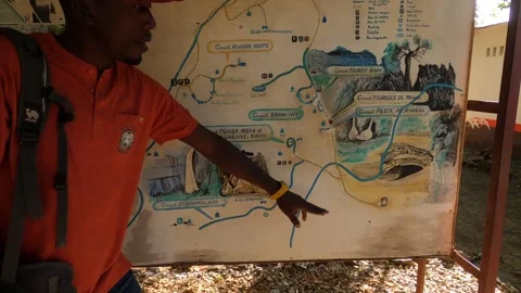 Malagasy male guide demonstrates on map the route to Circuit tsingy rary Video stock 310535365