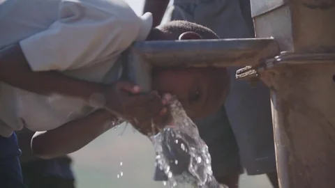 Malawi - November 2016: Boy drinking water from a pump Stock Footage 74390416