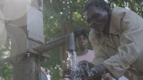 Malawi - November 2016: Old man washes his hands at the water pump Stock Footage 74390697