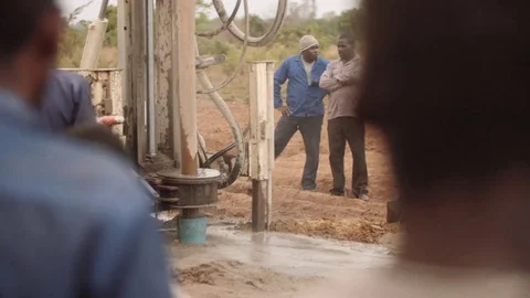 Malawi - November 2016: Rural community watching a borehole being drilled Stock Footage