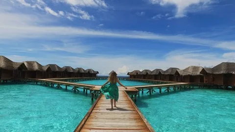 Maldive island resort. Girl in green dress walking on wooden bridge near Stock Footage