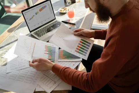 Male accountant working with documents using laptop reading report with gra.. Stock Photos