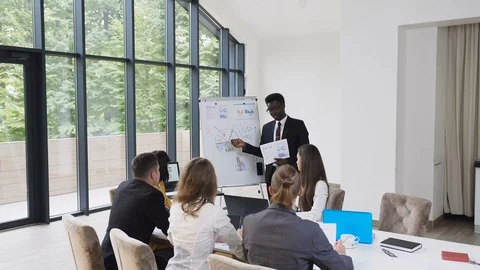 Male american-african manager presents on whiteboard new project plan to Stock Footage
