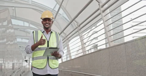 Male American engineer standing using tablet to inspect building construction Stock Footage 259813444