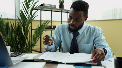 Male analyst working with financial documents and writing, sitting at table in Stock Footage 168739633