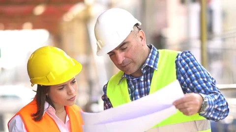 Male and female civil engineers holding plans and inspecting construction site Stock Footage