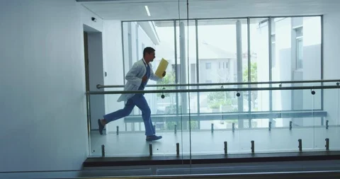 Male and female doctors running in the corridor at hospital Stock Footage
