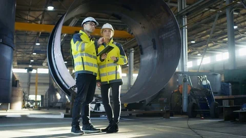 Male and Female Industrial Engineers in Hard Hats Discuss New Project  Stock Footage