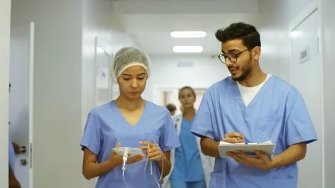 Male and Female Nurses Talking and Walking along Corridor Stock Footage