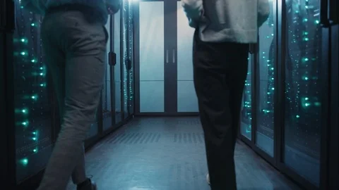 Male and female server specialists walking in working rack server room. Back of Stock Footage 119082753