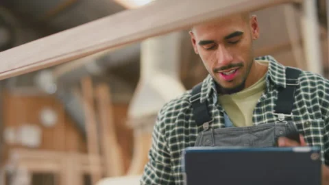 Male Apprentice With Digital Tablet Working As Carpenter In Furniture Workshop Video stock 242321042
