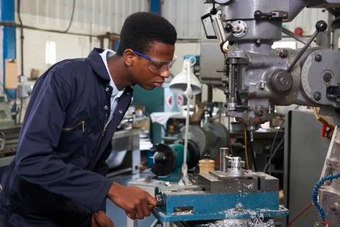 Male apprentice engineer working on drill in factory Foto stock