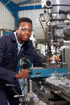 Male Apprentice Engineer Working On Drill In Factory 库存照片