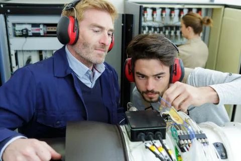 Male apprentice technician working under supervision Stock Photos