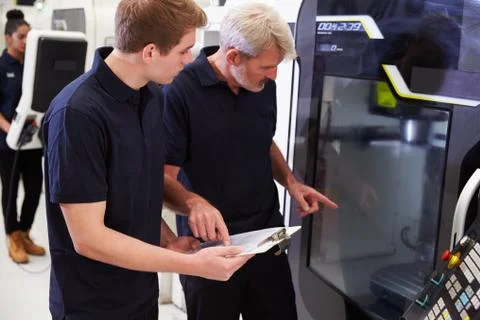 Male Apprentice Working With Engineer On CNC Machinery Foto stock