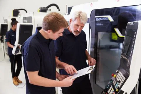 Male Apprentice Working With Engineer On CNC Machinery Foto stock