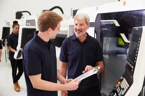 Male Apprentice Working With Engineer On CNC Machinery Foto stock