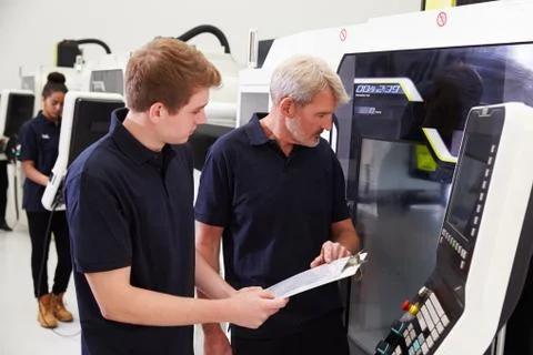 Male Apprentice Working With Engineer On CNC Machinery Foto stock