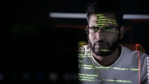 Male arabic hacker hacks computer in dark. Computer code reflecting on his face 스톡 동영상 69208016