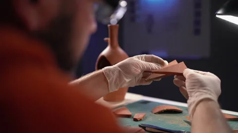 Male archeologist working late night in office and studying antique parts of Stock Footage 252147352