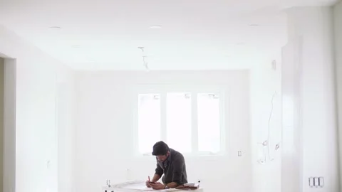 Male architect editing blueprints at table in new home Stock Footage 221041308