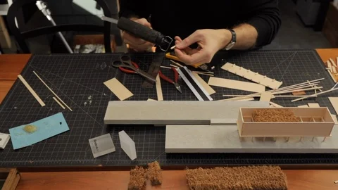 Male architect gluing and constructing a scale model of a modern residence Video stock 104442038