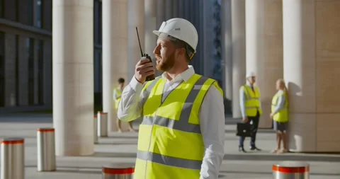 Male architect in hardhat using walkie-talkie at construction site Stock Footage 156449073